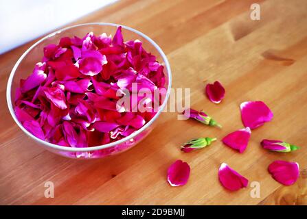 Petali di rosa in una ciotola di vetro situata su un tavolo di legno marrone. Pronto per la marmellata di rose. Foto Stock