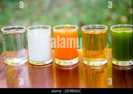 Succhi di frutta, succo d'arancia, succo di mela, succo di kiwifruit, con latte e acqua in vetro sul tavolo. Foto Stock