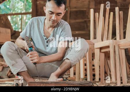 i lavoratori usano scalpelli per intagliare legno per mobili nel officina Foto Stock