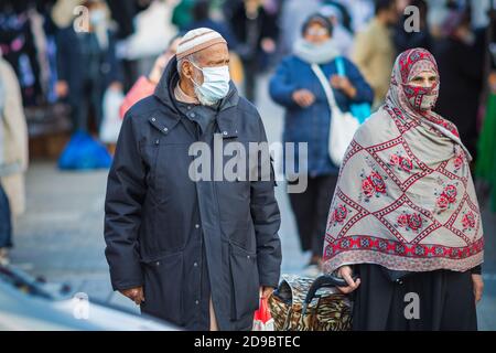 Londra, Regno Unito - 3 novembre 2020 - un uomo e una donna musulmani asiatici che indossano una maschera e un hijab come copertura facciale durante lo shopping al mercato di Walthamstow Foto Stock