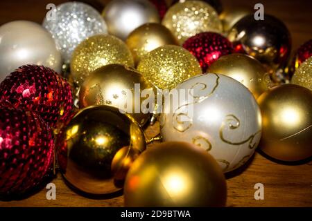 Una grande quantità di diverse palline di Natale di colore rosso, oro e crema di diverse texture, su un tavolo Foto Stock