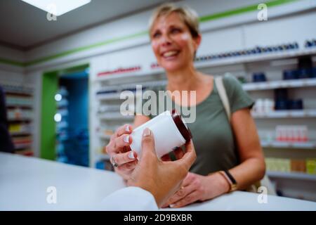 Madre caucasica che acquista sopra il contromicramento dalla razza mista farmacista interno Foto Stock