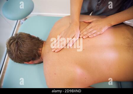 Fisioterapista femmina dando massaggio alla schiena al paziente di sesso maschile Foto Stock