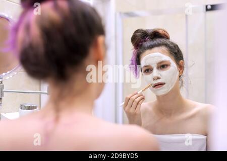Giovane bella donna con maschera cosmetica naturale guaritrice su faccia Foto Stock