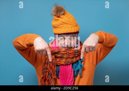 Uomo anziano con baffi che indossano diverse sciarpe e cappelli che puntano di lato Foto Stock