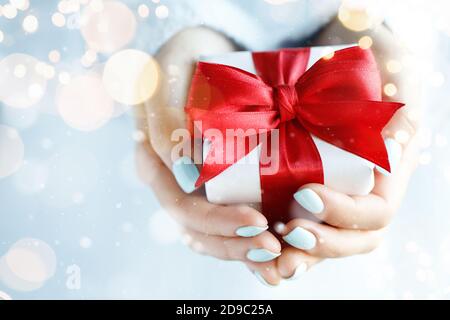 Confezione regalo con arco rosso in mani femminili Foto Stock