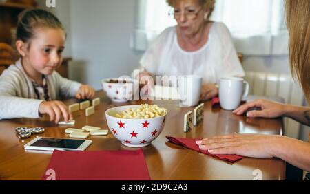 Tre generazioni femminili che giocano a domino Foto Stock