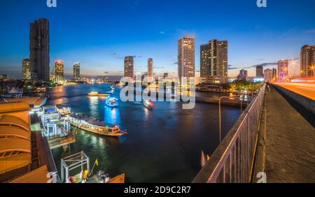 Grattacieli e traffico occupato sul fiume Chao Phraya a Bangkok, Thailandia, visto dal ponte Taksin al crepuscolo Foto Stock