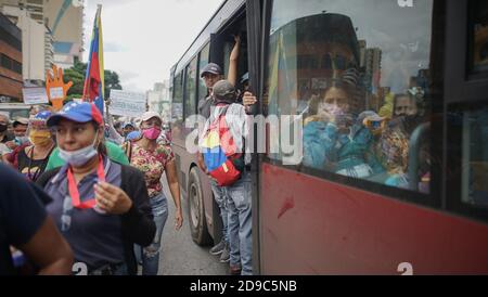 Caracas, Venezuela. 04Nov 2020. I conducenti di autobus con maschere guardano i dimostranti che passano con bandiere venezuelane nel mezzo della pandemia di Corona. Un'alleanza sindacale aveva chiesto una protesta da parte degli operatori sanitari e dell'istruzione per ottenere stipendi migliori. Credit: Rafael Hernandez/dpa/Alamy Live News Foto Stock