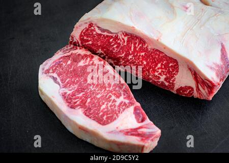 un pezzo di manzo crudo striscia di bistecca di lombo su un sfondo nero Foto Stock