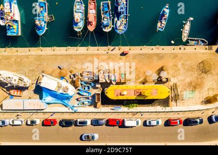 Scatto aereo di barche legate al lato del molo da lato con auto parcheggiate sulla strada Foto Stock