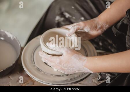 Primo piano di mani di donna che creano vaso di terra sul cerchio di vasaio. Foto Stock