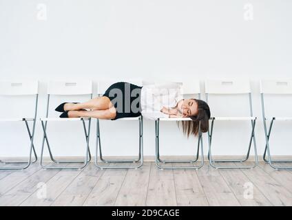 Una donna d'affari stanca e overworked che dormiva sulla sedia alla sala conferenze in ufficio Foto Stock