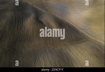 Vista aerea dall'alto sul campo coltivato arato ondulato toscano con pittoreschi punti di luce solare serale con texture che giocano gradualmente con l'ombra della luce. Beau Foto Stock