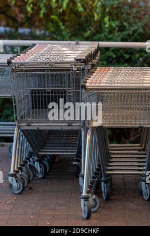carrello per lo shopping in file e impilato all'esterno di un supermercato in attesa di uso. Foto Stock