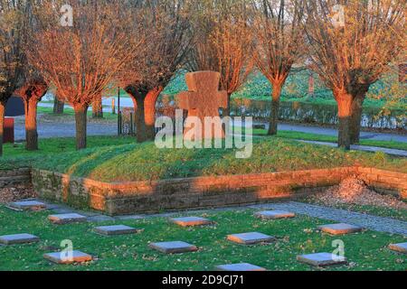 Croce di pietra e la prima guerra mondiale tombe al cimitero di guerra tedesco Langemark al tramonto a Langemark-Poelkapelle, Belgio Foto Stock