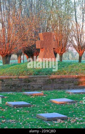 Croce di pietra e la prima guerra mondiale tombe al cimitero di guerra tedesco Langemark al tramonto a Langemark-Poelkapelle, Belgio Foto Stock