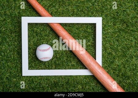 Baseball bat e palla su telaio isolato su un campo di erba. Disposizione piatta, vista dall'alto. Concetto di casa e allenamento online Foto Stock