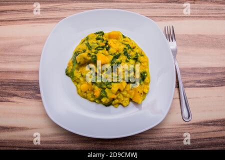 Una porzione di cibo indiano fatto di insalata con giallo salsa e mango serviti sul piatto bianco Foto Stock