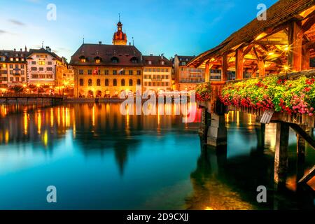 Il Ponte della Cappella fiorito di Lucerna di notte si riflette sul fiume. Incredibile vita notturna della città di Lucerna illuminata di notte sul lago di Lucerna, Svizzera Foto Stock