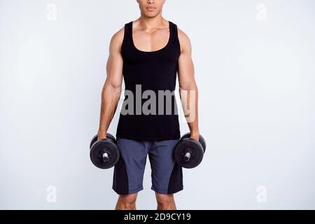 Ritratto con vista ritagliata del suo bel contenuto sportivo serio ragazzo forte che fa l'esercitazione che tiene nelle mani due dumbbell stile di vita Foto Stock