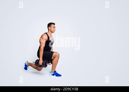 Vista a tutta lunghezza del corpo del suo bell'attraente ragazzo sportivo muscolare facendo esercizio di sollevamento del peso di costruzione del corpo isolato su grigio chiaro Foto Stock