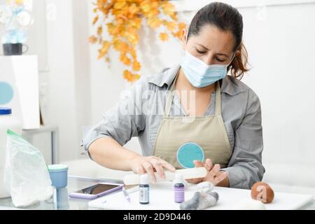 Pasticciere lavorando con fondente per decorare una torta - Donna cucina con maschera - Donna pittura argilla con coloranti Foto Stock