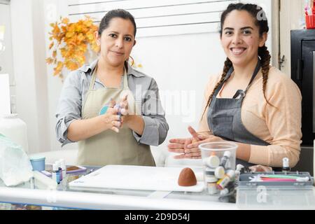 Donne latine che lavorano nella loro panetteria - donne pasticcerie chef Lavorare con fondente per decorare una torta - donne ispaniche imprenditori Foto Stock