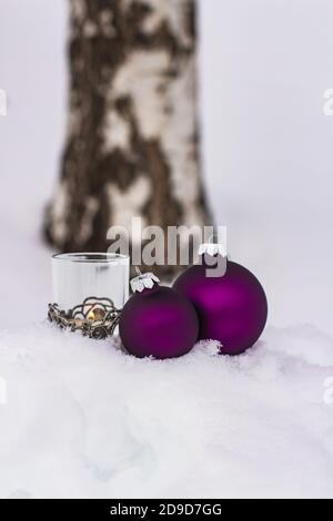 palline di natale viola e candela nella neve; cartolina di natale con spazio di copia Foto Stock