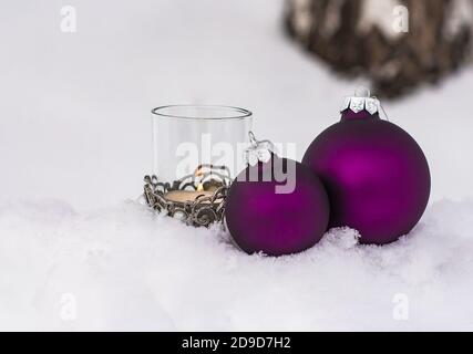 palline di natale viola e candela nella neve; cartolina di natale con spazio di copia Foto Stock