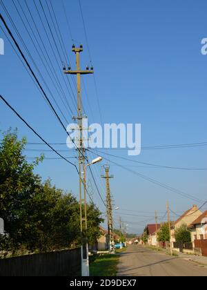 Strada nel vecchio villaggio rumeno Aurel Vlaicu, con vecchio tradizionale case e fattorie, pali e fili elettrici Foto Stock