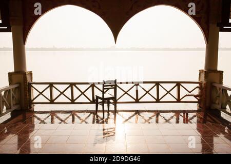 Un tranquillo vecchio padiglione accanto al fiume Mekong al tramonto, vuoto vecchio padiglione con vista in legno sedia dall'interno verso l'esterno. Champasak, Laos. Foto Stock