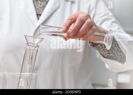 l'assistente di laboratorio versa il liquido in un primo piano della provetta Foto Stock