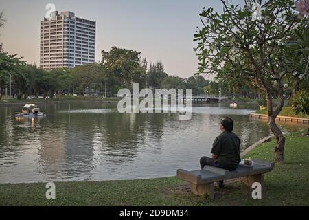 Bangkok, Thailandia, febbraio 2009. Un uomo seduto su una panchina guarda il lago nel Parco Lumpini. Foto Stock