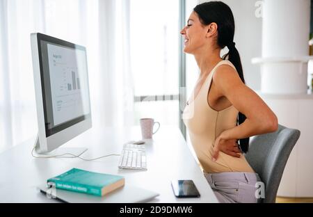 Oberati di lavoro donna con dolore alla schiena in ufficio con una postura sbagliata Foto Stock