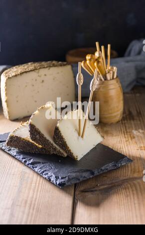 Formaggio semi-stagionato con un sottile strato di erbe aromatiche. Tipico spuntino della cucina mediterranea Foto Stock