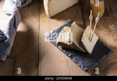 Formaggio semi-stagionato con un sottile strato di erbe aromatiche. Tipico spuntino della cucina mediterranea Foto Stock