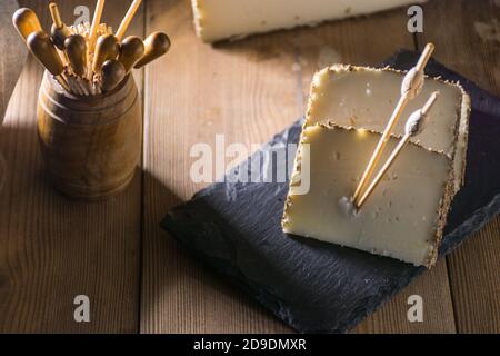 Formaggio semi-stagionato con un sottile strato di erbe aromatiche. Tipico spuntino della cucina mediterranea Foto Stock