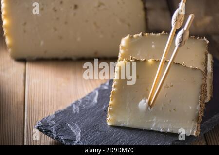 Formaggio semi-stagionato con un sottile strato di erbe aromatiche. Tipico spuntino della cucina mediterranea Foto Stock