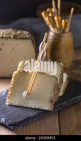 Formaggio semi-stagionato con un sottile strato di erbe aromatiche. Tipico spuntino della cucina mediterranea Foto Stock