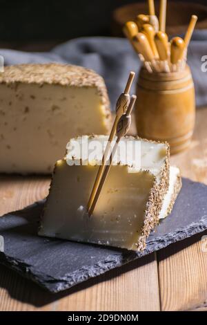 Formaggio semi-stagionato con un sottile strato di erbe aromatiche. Tipico spuntino della cucina mediterranea Foto Stock