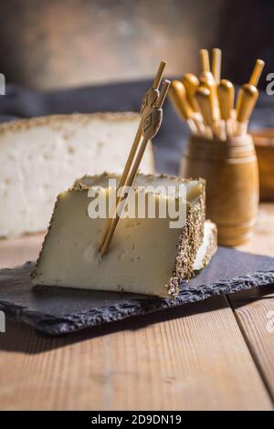 Formaggio semi-stagionato con un sottile strato di erbe aromatiche. Tipico spuntino della cucina mediterranea Foto Stock