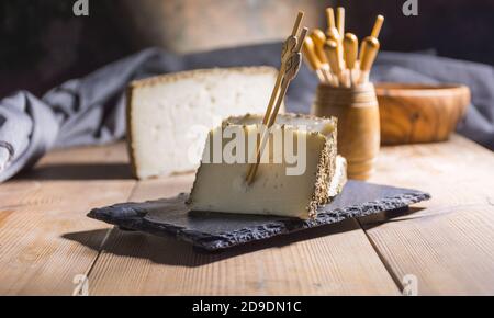 Formaggio semi-stagionato con un sottile strato di erbe aromatiche. Tipico spuntino della cucina mediterranea Foto Stock