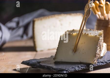 Formaggio semi-stagionato con un sottile strato di erbe aromatiche. Tipico spuntino della cucina mediterranea Foto Stock