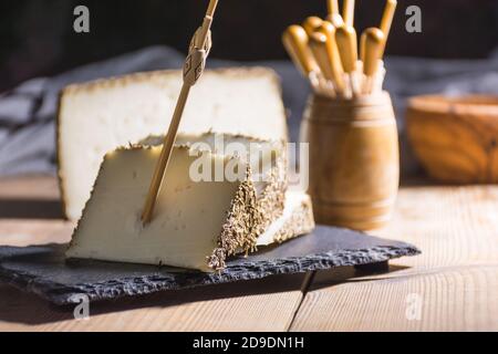 Formaggio semi-stagionato con un sottile strato di erbe aromatiche. Tipico spuntino della cucina mediterranea Foto Stock