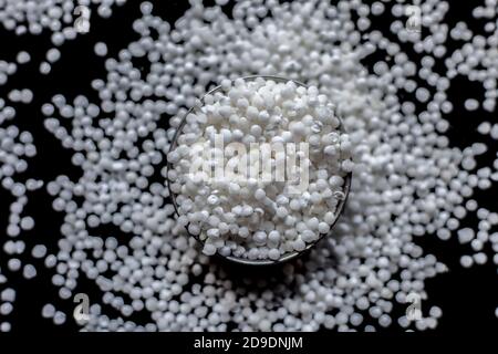 Primo piano di perle di sago grezze o di perle di tapioca in una lastra di vetro su una superficie di colore nero. Foto Stock