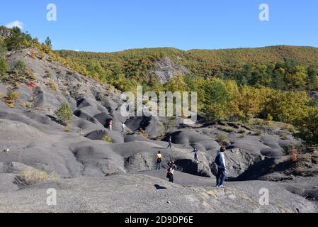 Bambini che giocano sulle formazioni di Black Marl conosciute come Robines in Il Geopark di alta Provenza vicino Digne-les-Bains Alpes-de-Haute-Provence Francia Foto Stock