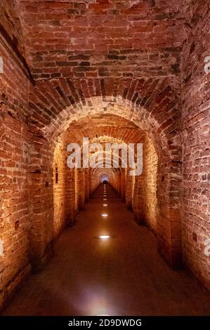 Arco in mattoni rossi come passaggio tra le due ali di un castello medievale. Granito pietra un mattone costruito passaggio interno ai bastioni Foto Stock