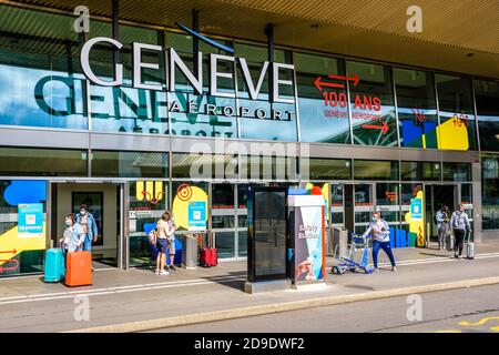 I passeggeri in attesa o a piedi davanti all'ingresso dell'aeroporto internazionale di Ginevra (GVA), che celebra il suo centenario nel 2020. Foto Stock