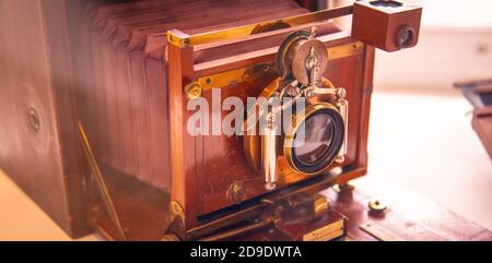 Obiettivo della vecchia fotocamera retrò primo piano su un tavolo di legno. Immagine closeup di lenti in pellicola di legno antica Foto Stock